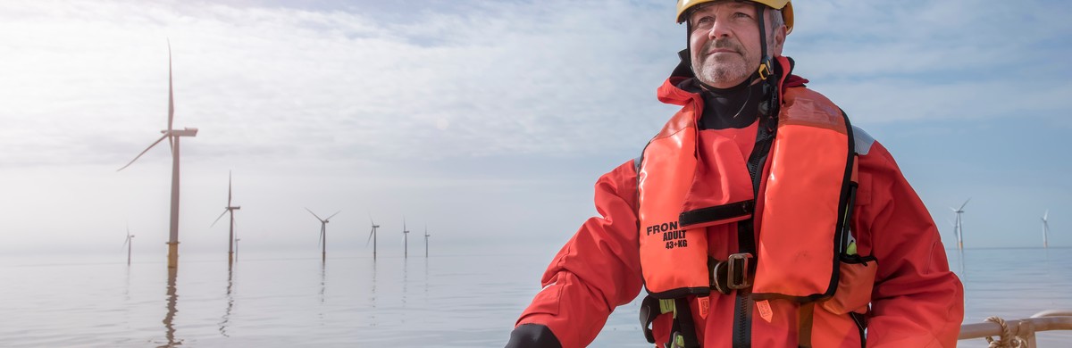 Engineer wearing PPE and lifejacket on a boat at an offshore windfarm