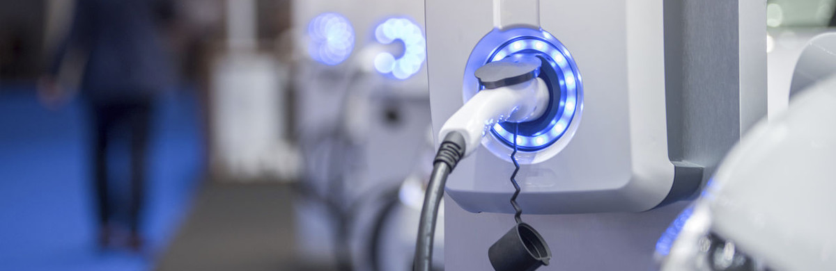 Electric vehicle charging point in garage with man walking away in background - used for the National Grid article 'Smart ways to shift the journey towards EVs for everyone into the fast lane'