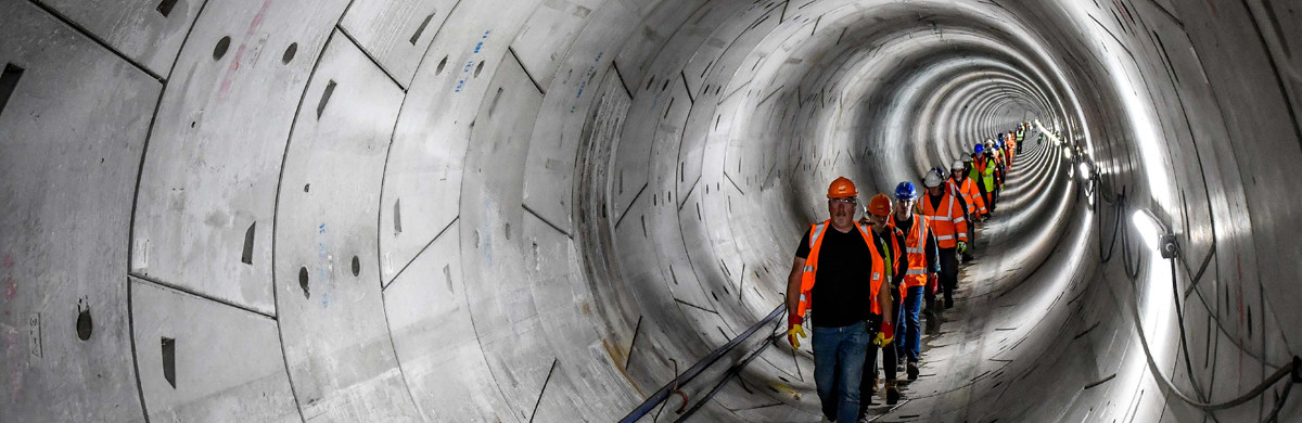 A line of people wearing hard hats and high-vis walking through the Humber Tunnel - used for the National Grid story 'Celebrating the completion of the Humber Tunnel'