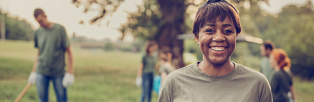 Black woman with group of volunteers cleaning nature together