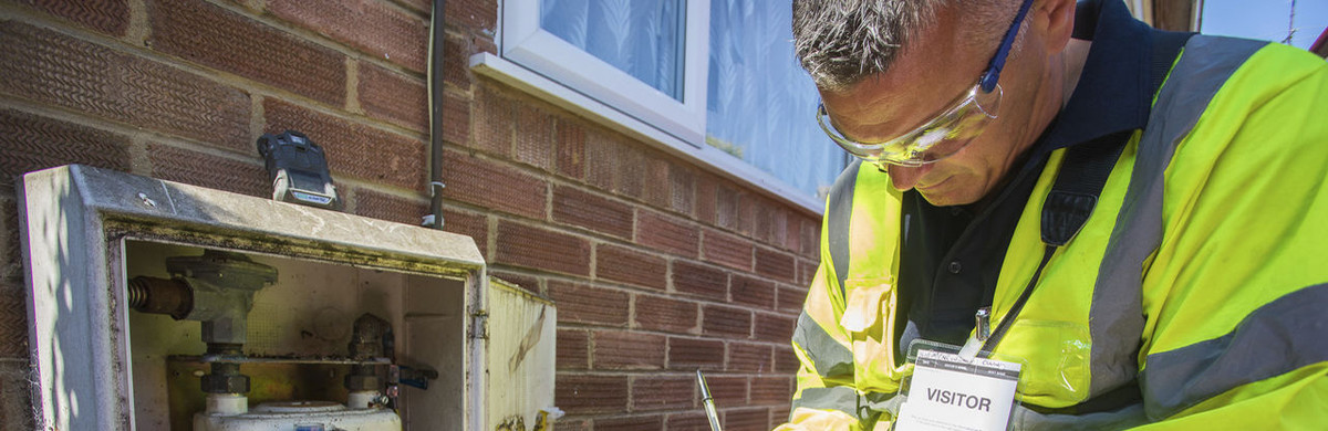 Metering engineer in high-vis jacket in front of gas meter - used for the National Grid story 'Why meters matter in a time of crisis'
