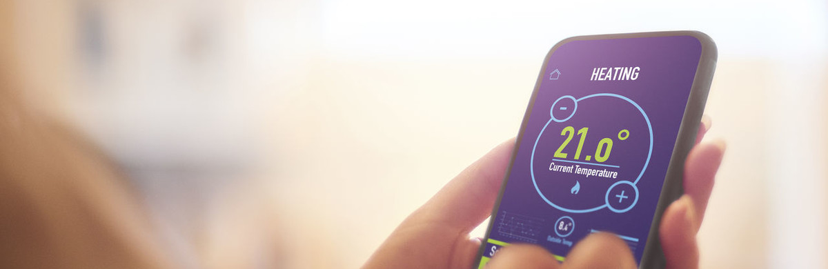 Hands holding a smart device showing heating and current temperature information - used for the National Grid story 'The future of home heating in a net zero UK'