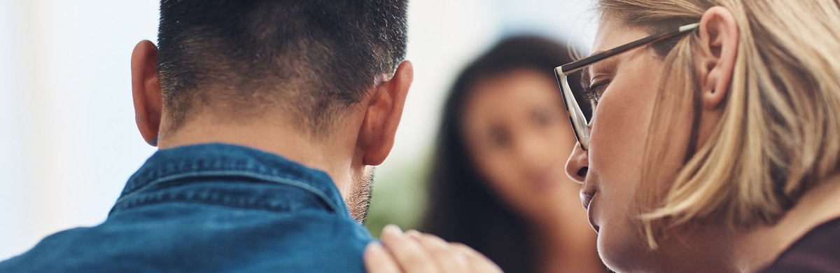 Woman talking to a man with her hand on his shoulder