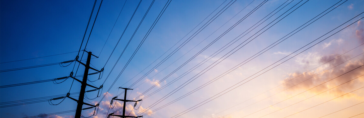 Silhouettes of power lines against blue sky at sunset