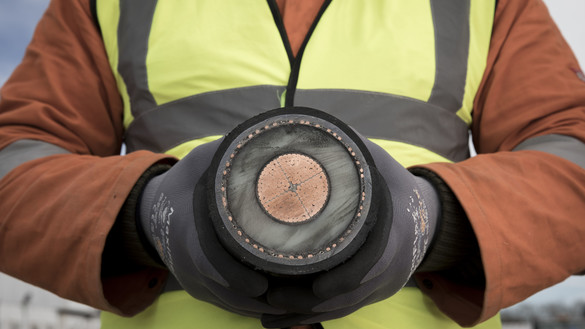 An image of a man wearing a hi-vis jacket and holding a cable