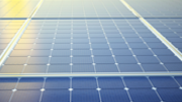 A close up of solar panels with clouds and the sun in the background