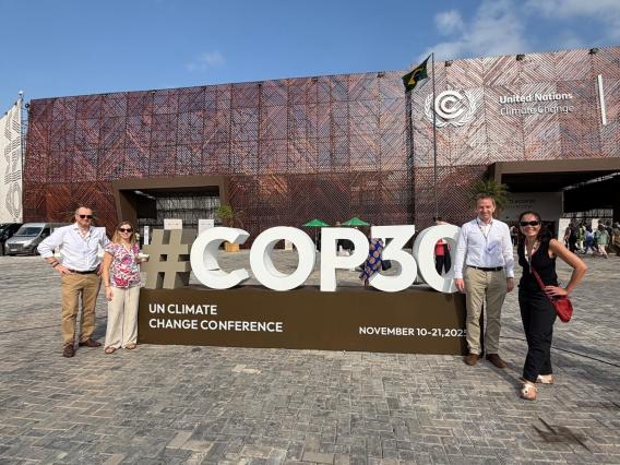 People standing by a sign that says COP30