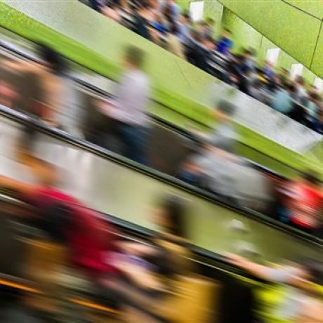 Blurred people on a moving escalator with a bright green background 