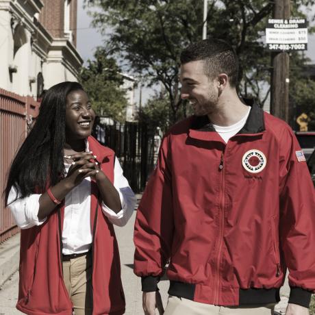Two young people smiling and walking down an American sidewalk