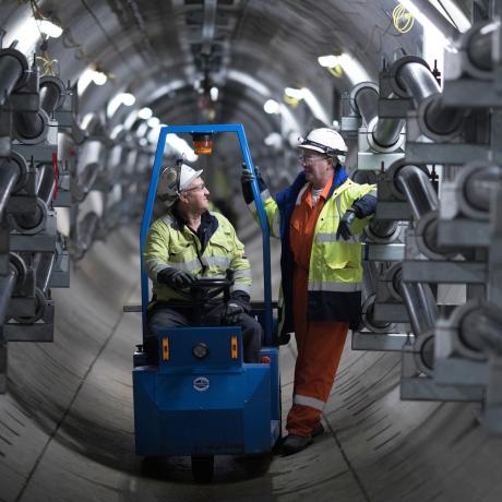 Two National Grid employees talking inside a grey tunnel space 