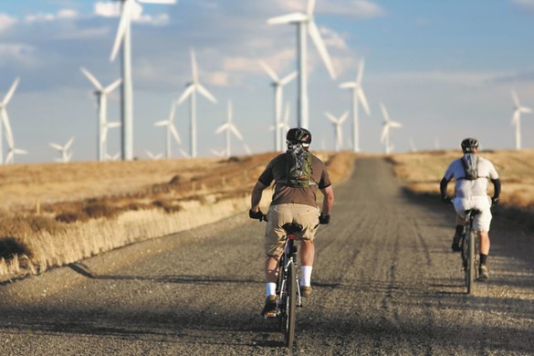 2 men cycling by some wind turbines