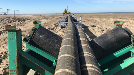 New electricity interconnector cables being pulled across a beach out to sea