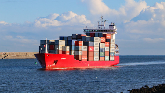 A red ship loaded with containers coming in to the Port of Tyne