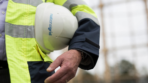 Partial view of a National Grid worker with an out of focus gas works structure in the background