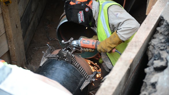 National Grid worker performing maintenance on an underground pipe 
