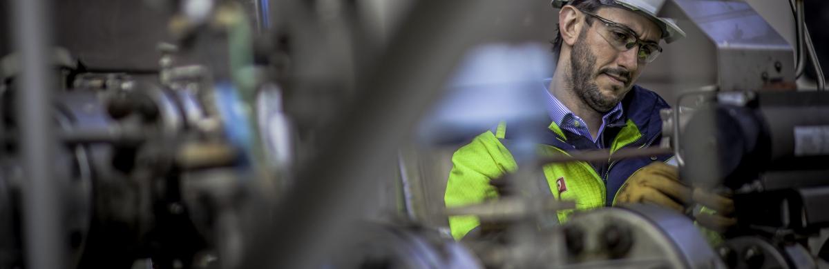 An image of a National Grid employee in protective gear working surrounded by machinery